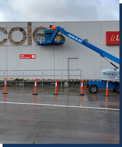 A boom lift with BT Access Group branding assisting with the removal of Coles signage